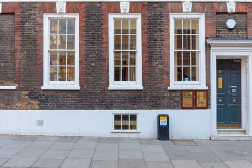 Street view of a classic brick facade with elegant wooden windows and door in an urban setting.